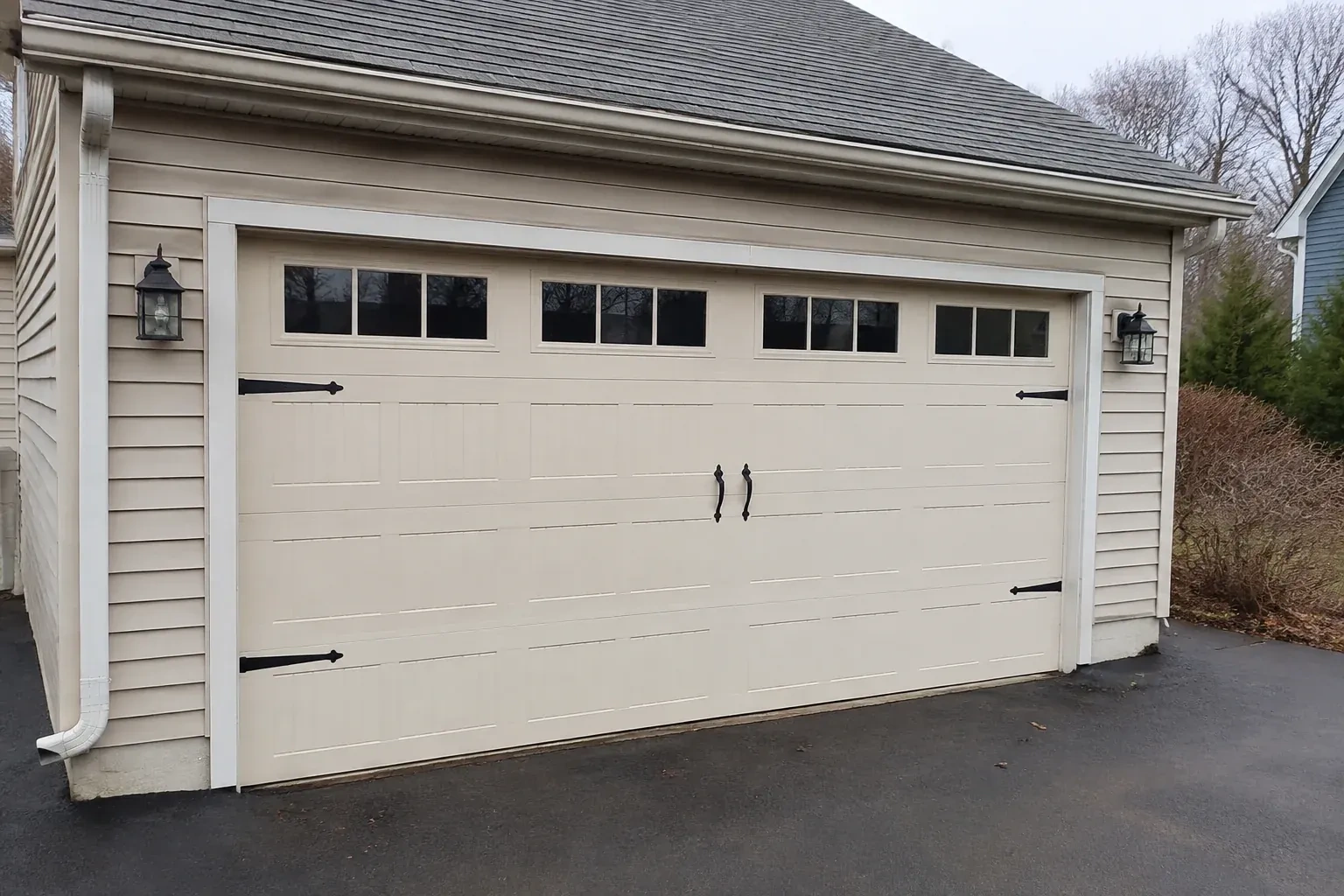Cream carriage-house-style garage door with dark decorative hardware. — Carriage-House Garage Door Installation, Orillia