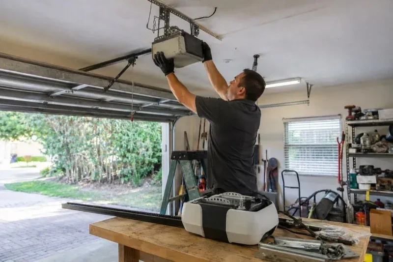 Person holding an overhead garage-door opener beside another opener and hardware on a workbench — Garage Door Opener Replacement, Ramara